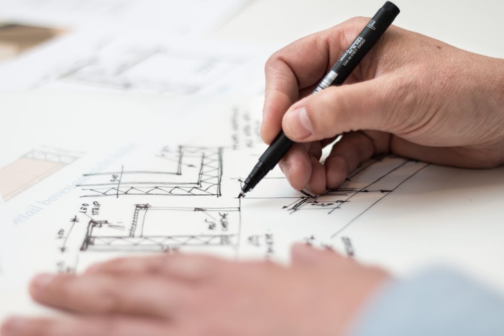 Advantages - Close-up of hand drawing intricate technical designs on blueprint with pen, ideal for engineering or architecture themes.